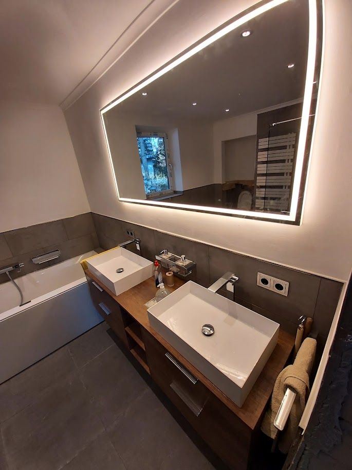 Badezimmer mit hinterleuchtetem Spiegel und Deckenspots